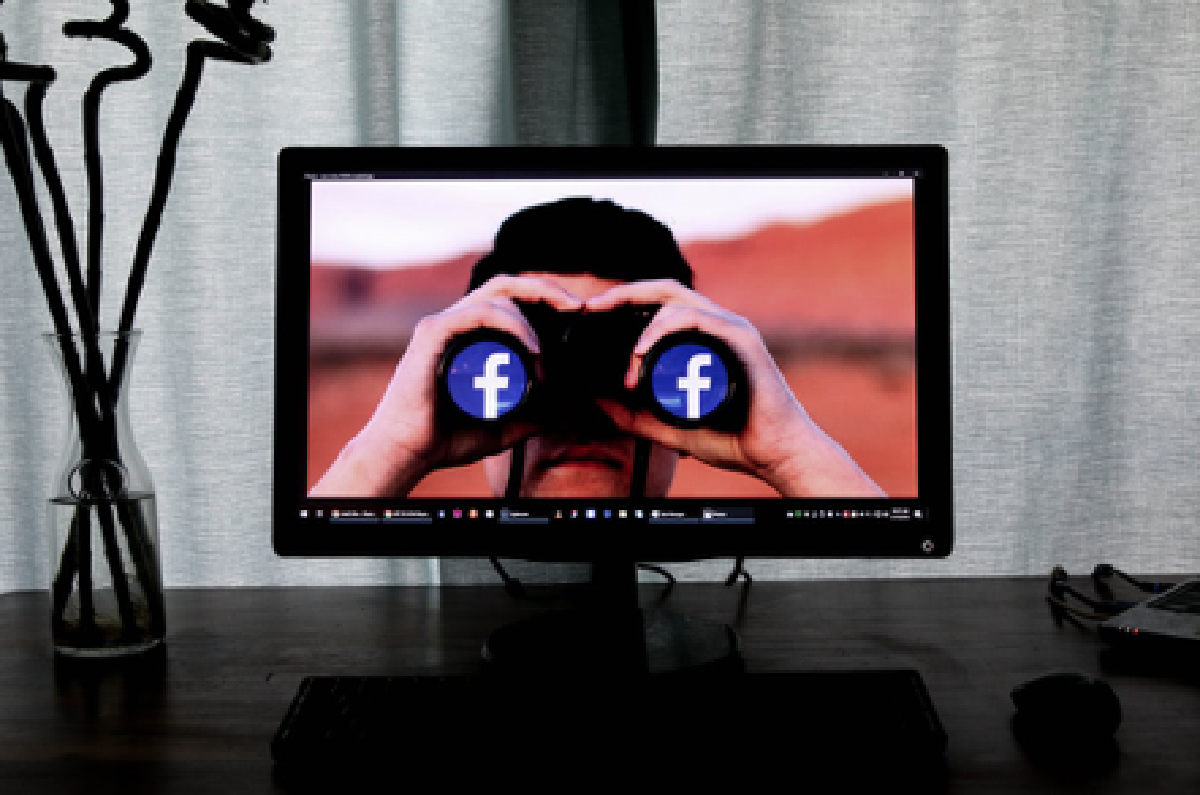 a man holding binoculars with the Facebook logo in place of the lenses
